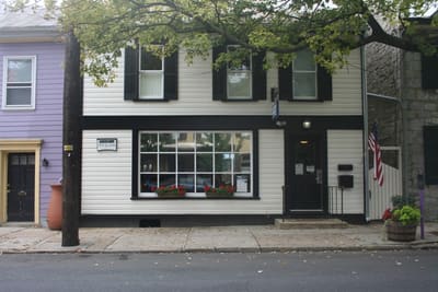 White clapboard storefront with black shutters in downtown Carlisle